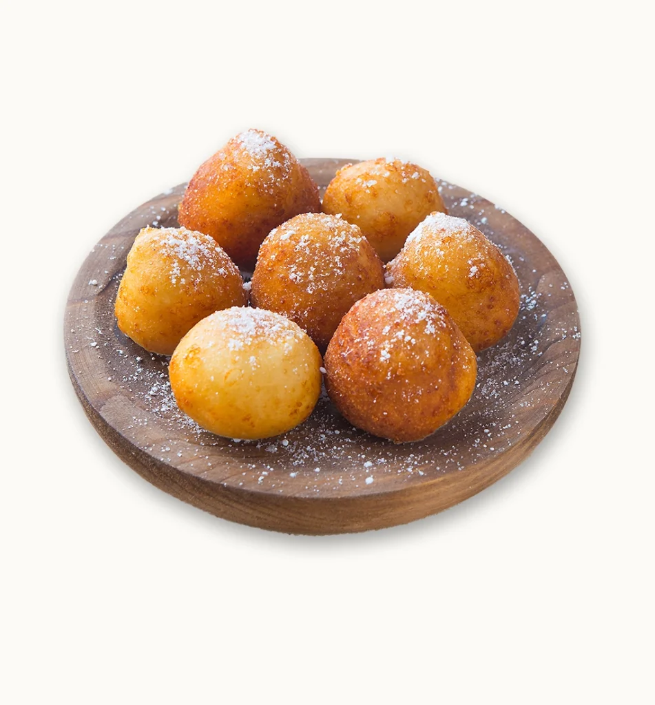 Buñuelos con azúcar glas espolvoreado en plato de madera